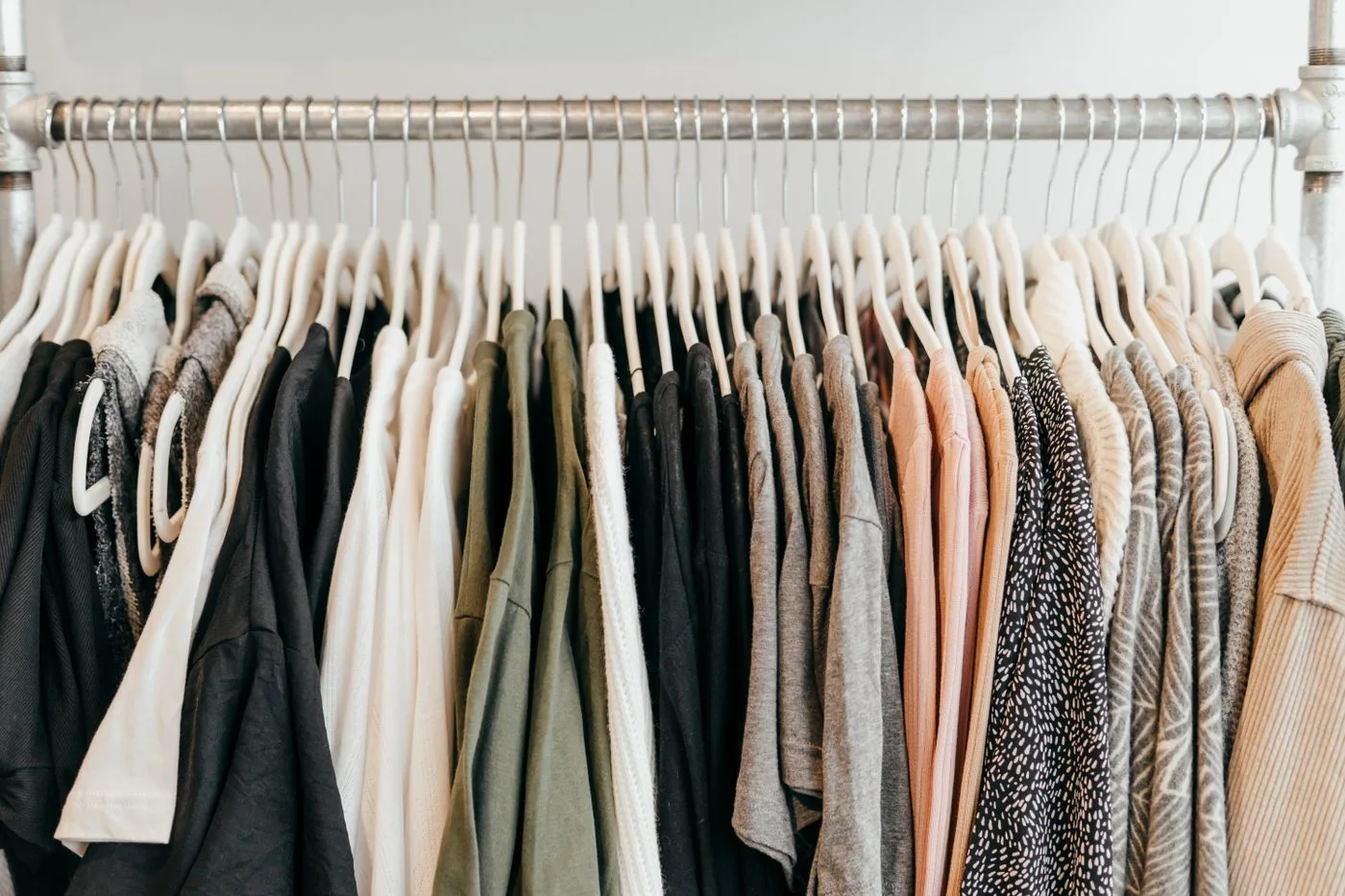 Pale and dark garments on hangers along a long clothing rail.