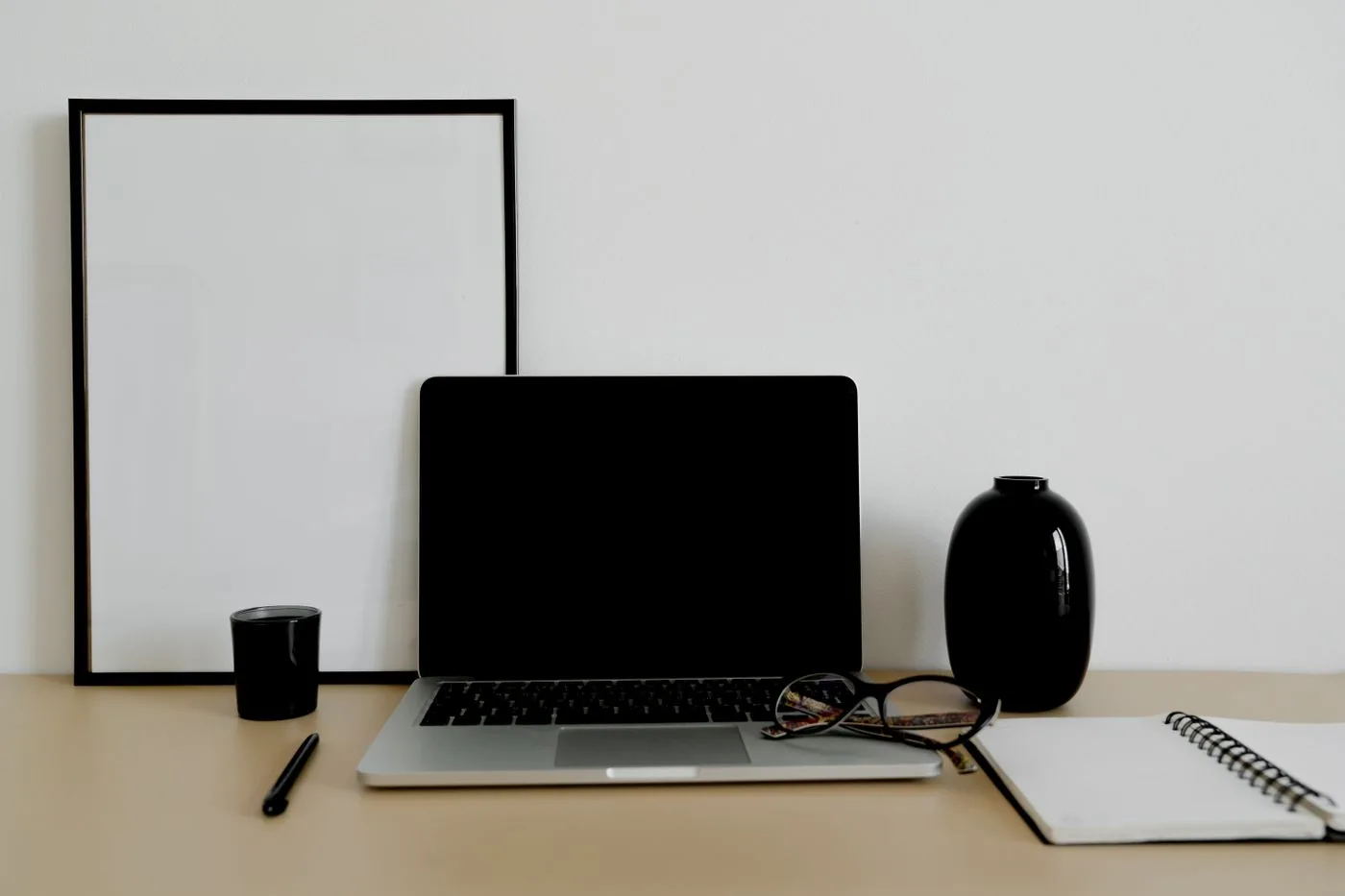 Laptop and notebook arranged on a small tidy desk