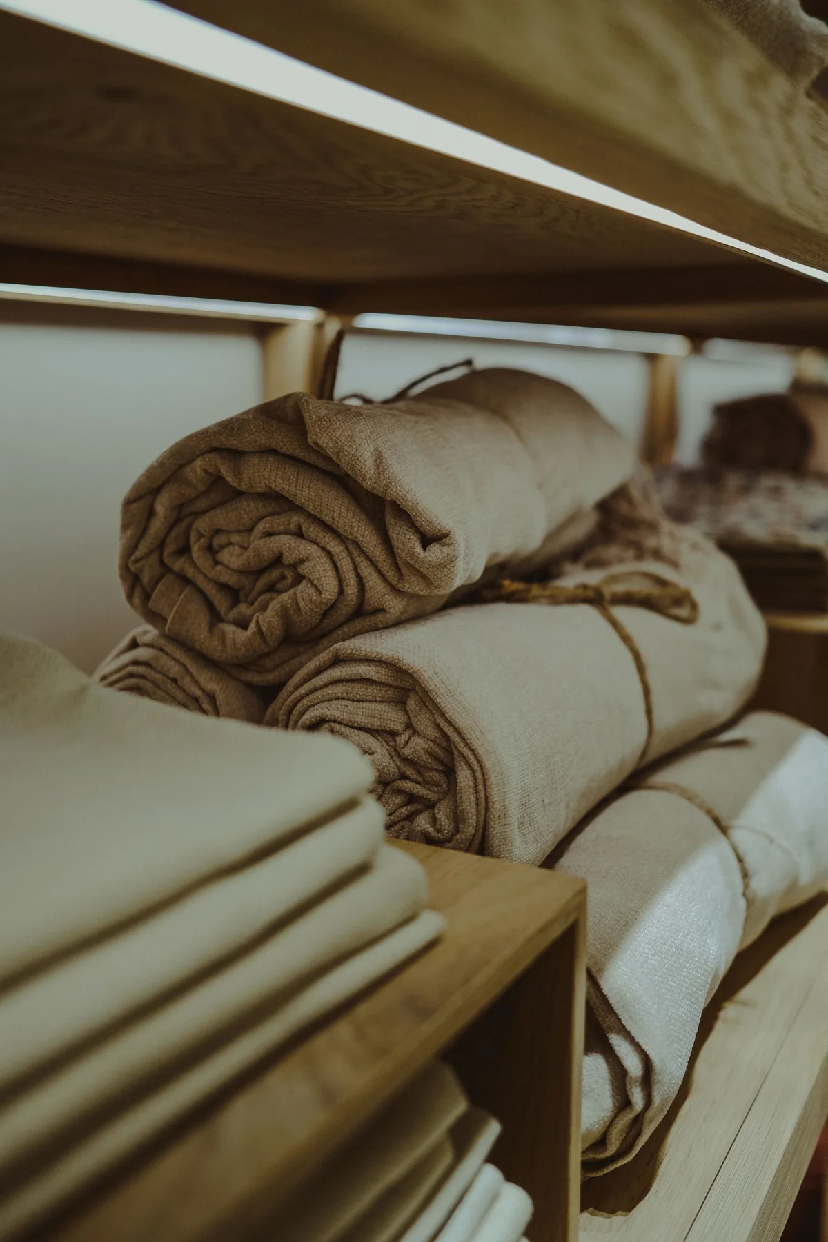 Rolled towels stacked on a wooden shelf.