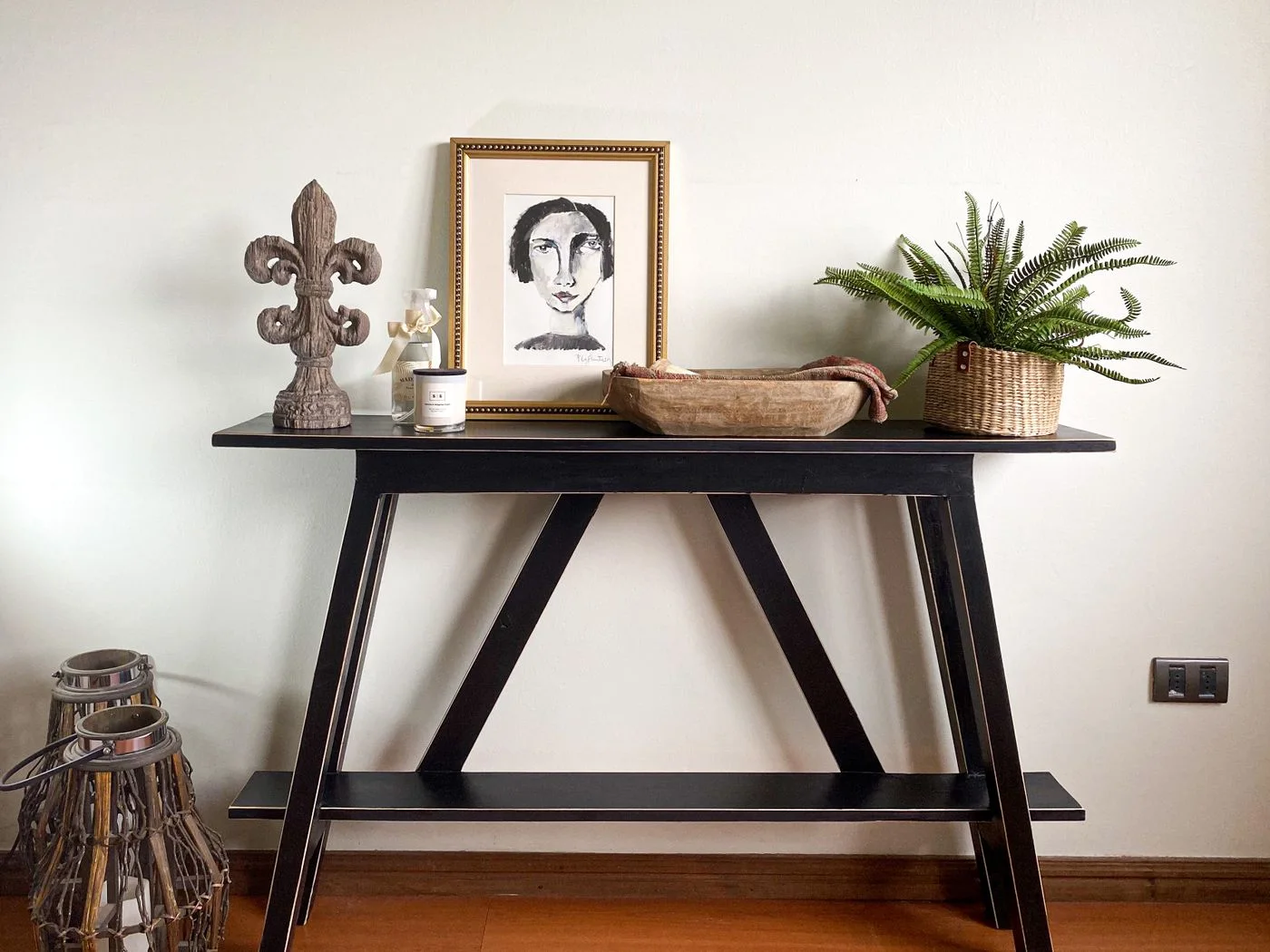 A framed print and decorative objects arranged on a black console table.