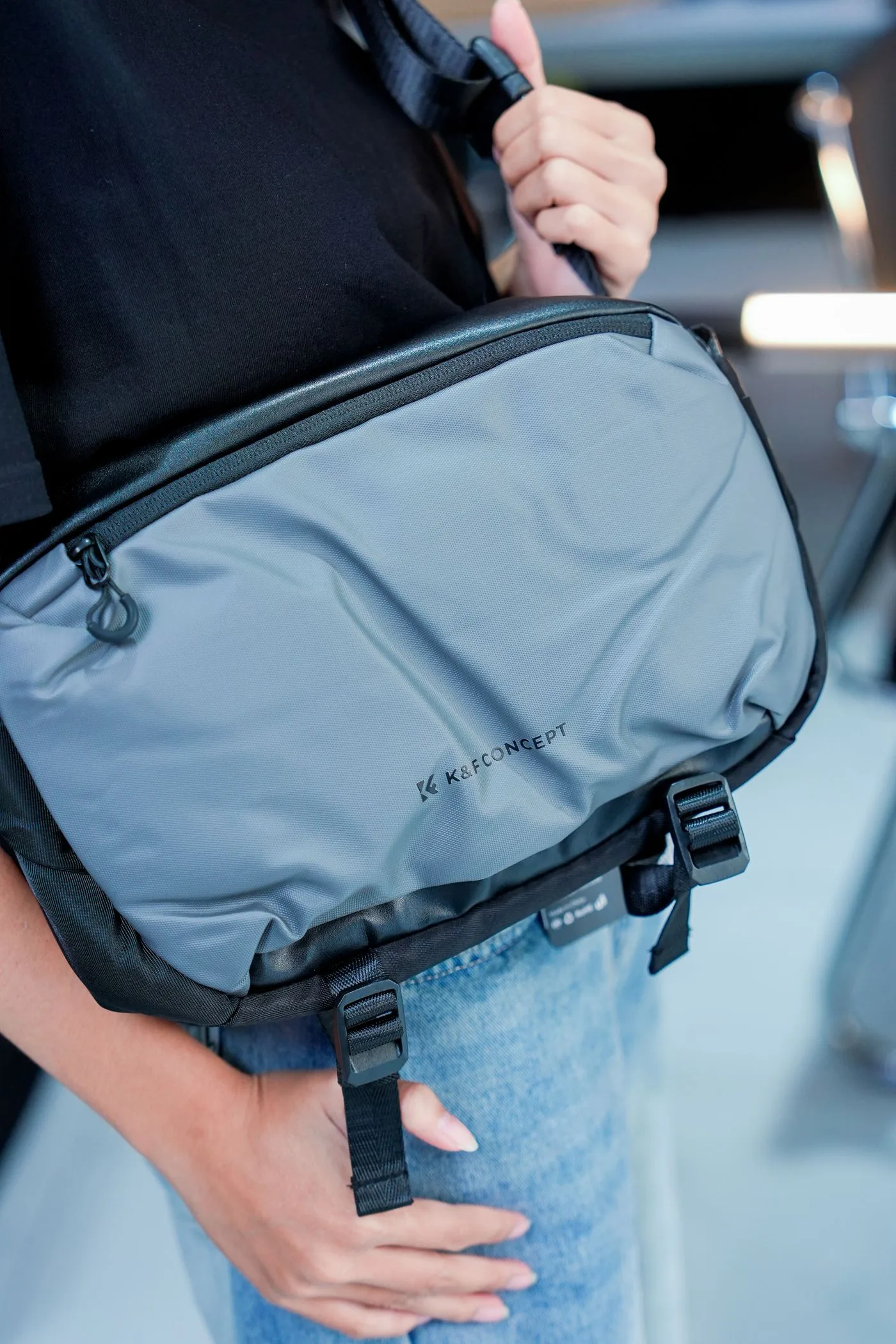 A blue crossbody bag worn over casual clothing.