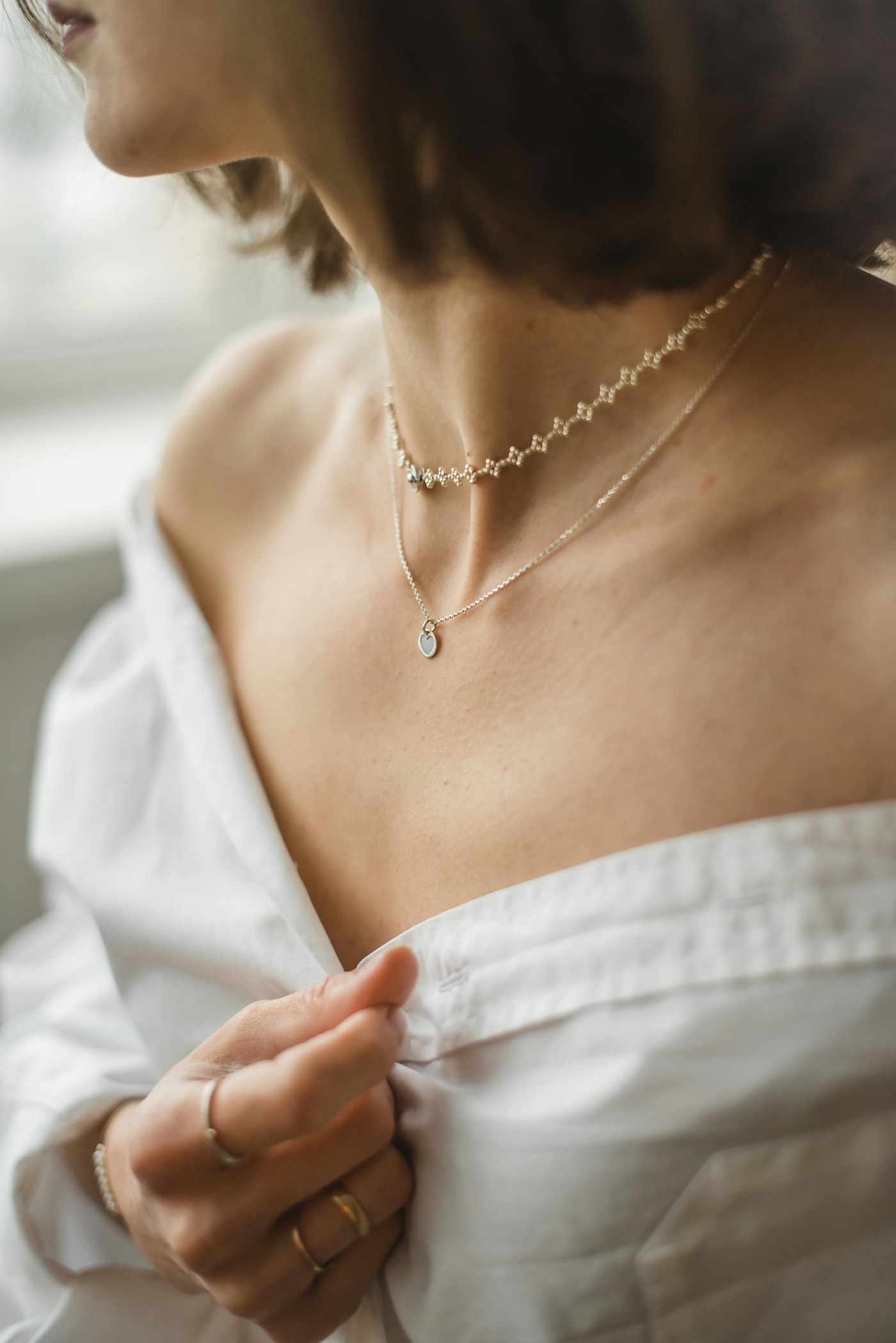 Layered necklaces worn above a white neckline.