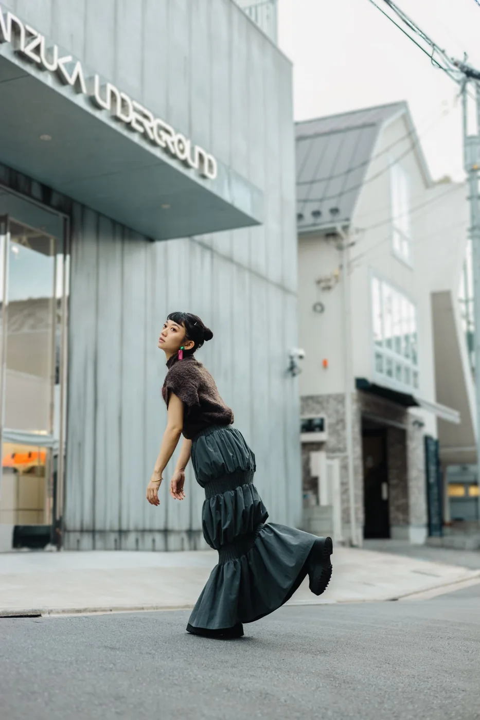 A woman wearing a dark tiered long skirt on a city street.
